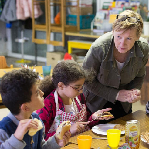 An adult volunteer assists children with their lunch. Photo courtesy Connectional Table. An adult volunteer assists children with their lunch. Photo courtesy Connectional Table.