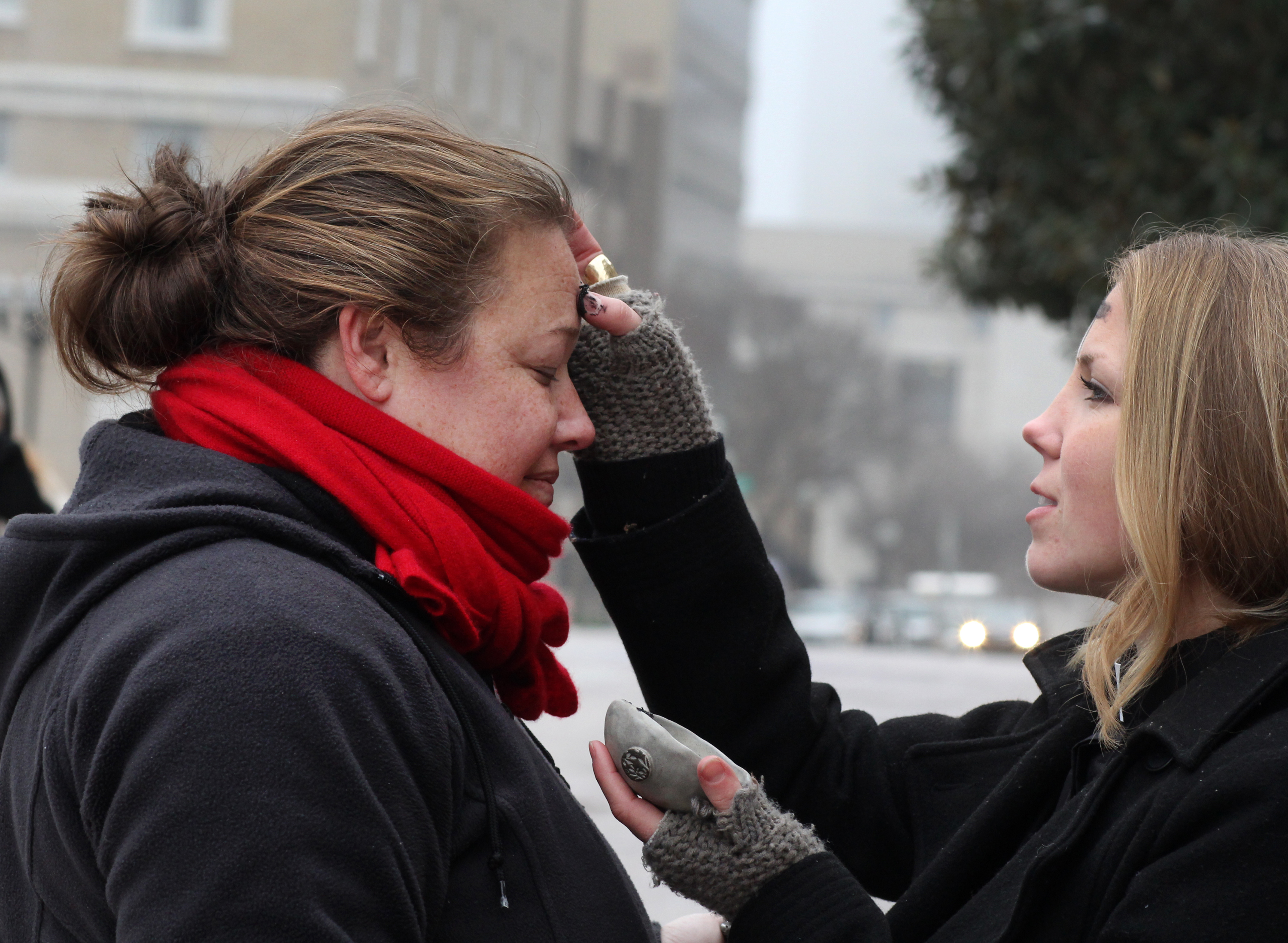 The Rev. Ingrid McIntyre receives ashes from street chaplain, Lindsey Krinks. About 30 people gathered as a community to share in the Ash Wednesday liturgy and to raise awareness of those suffering from homelessness and poverty. A file photo by Kathleen Barry, UMNS.