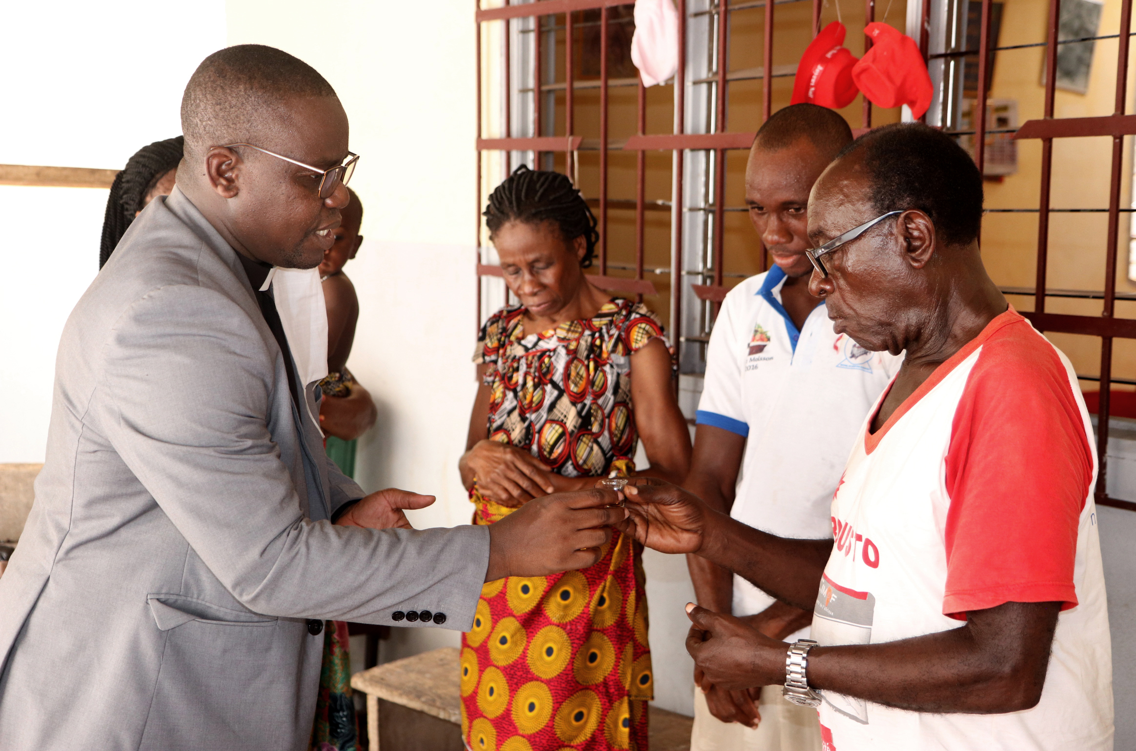 The The Rev. Isaac Broune (left), pastor of Bethel Quartier-Eléphants in Abidjan, Côte d’Ivoire, shares Communion with the Ohouo family (from left, Appolos, Fabrice, Chiadon and Chantal)  during a service in their home. While churches are closed because of the COVID-19 pandemic, members are conducting services at home with resources provided by their pastors. Photo by John Mel, UM News.