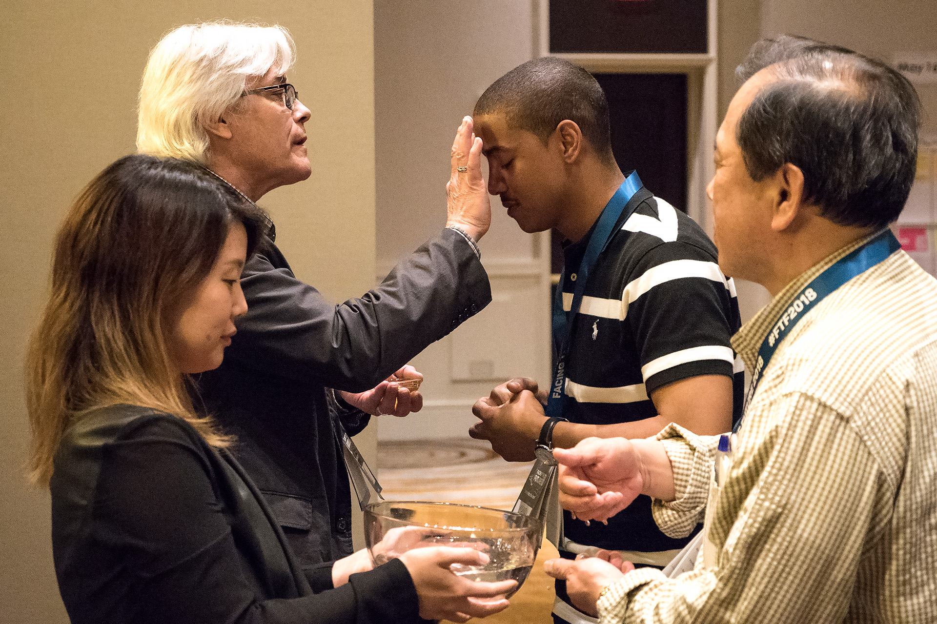 The Rev. Jerome R. DeVine (left, rear) makes the sign of the cross on the Rev. Kyland Dobbins during a reaffirmation of baptism at Facing the Future 2018, an event for clergy in cross-racial/cross-cultural appointments, in Newark, N.J. DeVine described the service as “both a remembering of how we are claimed by God's grace in baptism as well as the ongoing gift of grace that heals and strengthens us in the midst of the storms of life and ministry.” File photo by Joey Butler, UMNS.