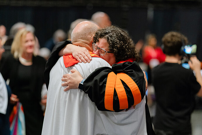 The Rev. Beth Stroud (right) hugs Bishop John Schol after she was reinstated as clergy on May 21, 2024, during a closed clergy session of the Eastern Pennsylvania Annual Conference in Wildwood, N.J. Stroud was defrocked 20 years ago after admitting to being in a committed relationship with another woman. “Wesleyan Vile-tality,” a new book by Ashley Boggan, makes its case partially by critiquing times that Boggan believes Methodists have fallen short, including the denomination’s longtime debate over how inclusive to be of LGBTQ people in the life of the church. File photo by Shari DeAngelo, courtesy of the Eastern Pennsylvania Conference.