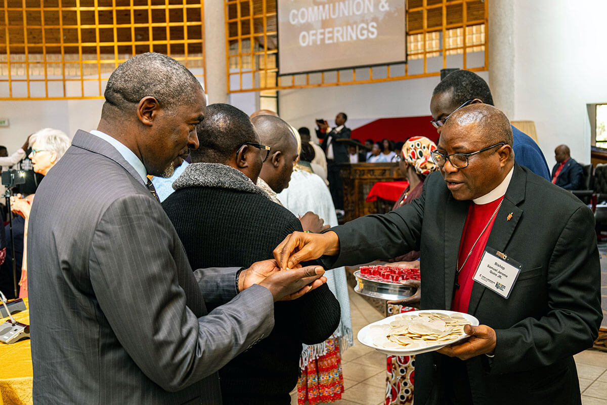 L'évêque du Libéria Samuel J. Quire Jr. (à droite) partage la communion avec le vice-chancelier de Africa University Peter M. Mageto (à gauche) pendant le culte lors de la formation quadripartite de la GCFA à Mutare, au Zimbabwe. L'agence financière de l'Eglise a réuni des responsables d'Eglise en Afrique pour discuter de la gestion des biens, des finances et des données. Avec l'aimable autorisation du Bureau des affaires publiques de Africa University.