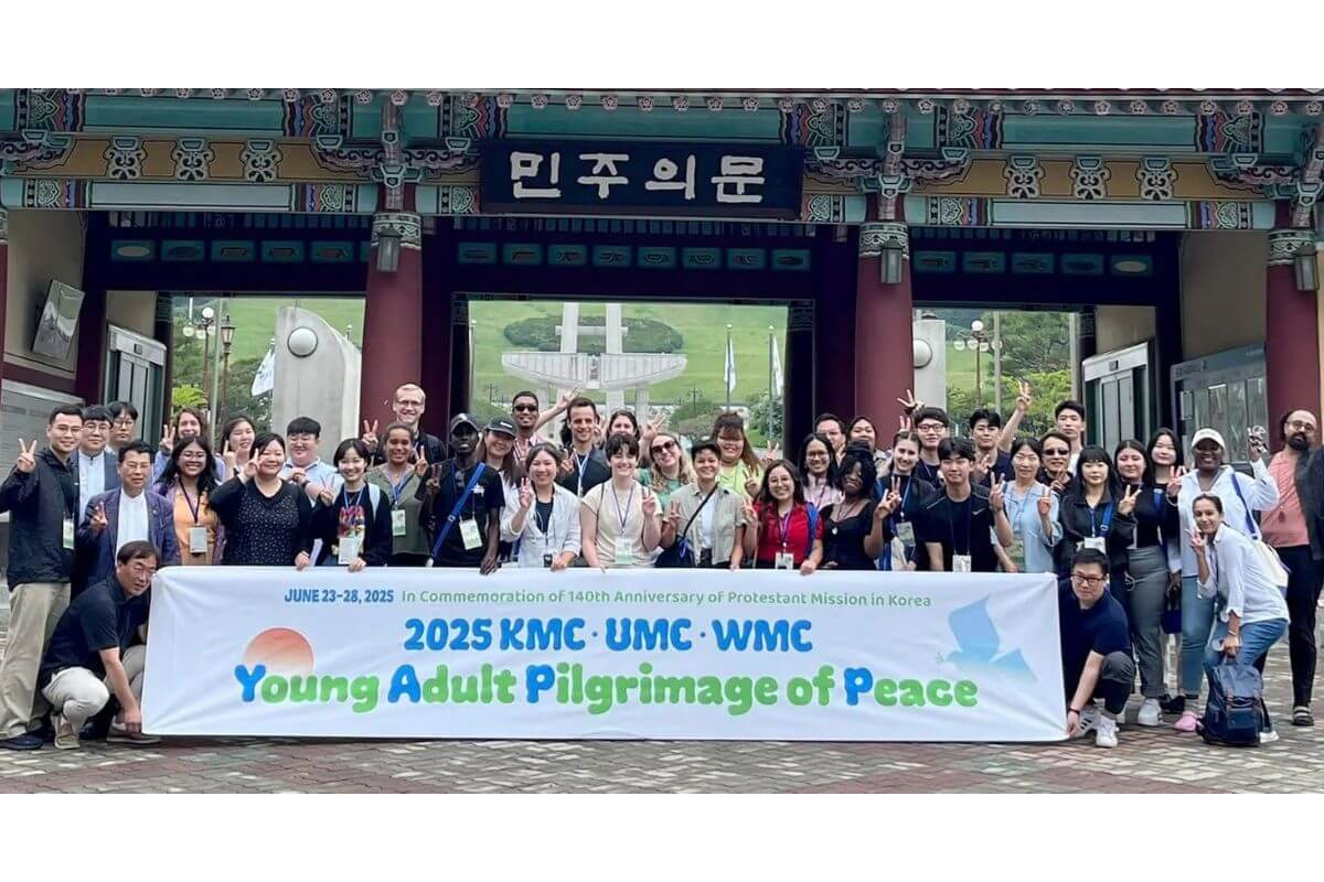 Members of the Young Adult Pilgrimage of Peace team huddle in the rain to hear a witness at Gollyeonggol Memorial Park in Daejeon, South Korea, where the first battle of the Korean War occurred, June 1950. Photo courtesy of Thomas Kim, UM News.