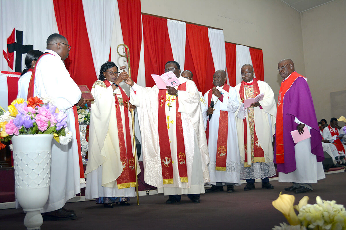 L'Évêque Mujinga Kashala (au centre) reçoit le marteau de l'évêque sortant Kasap Owan lors de la cérémonie d'installation de l'évêque Mujinga à la paroisse méthodiste unie Mémorial du Centenaire de Lubumbashi, en République démocratique du Congo. L’Évêque Mujinga Kashala Marie-Jeanne a été installée ce dimanche 17 août à Lubumbashi devient la première femme évêque élue en Afrique centrale et la deuxième sur le continent africain. Photo de Honoré Nkulu Dianda Photo UM News.